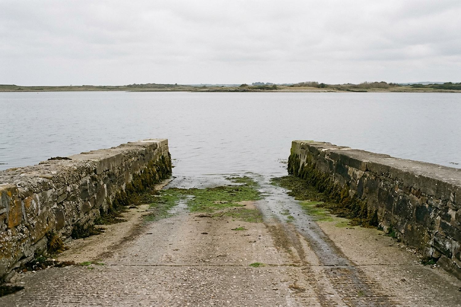A concrete slipway running down into calm water.