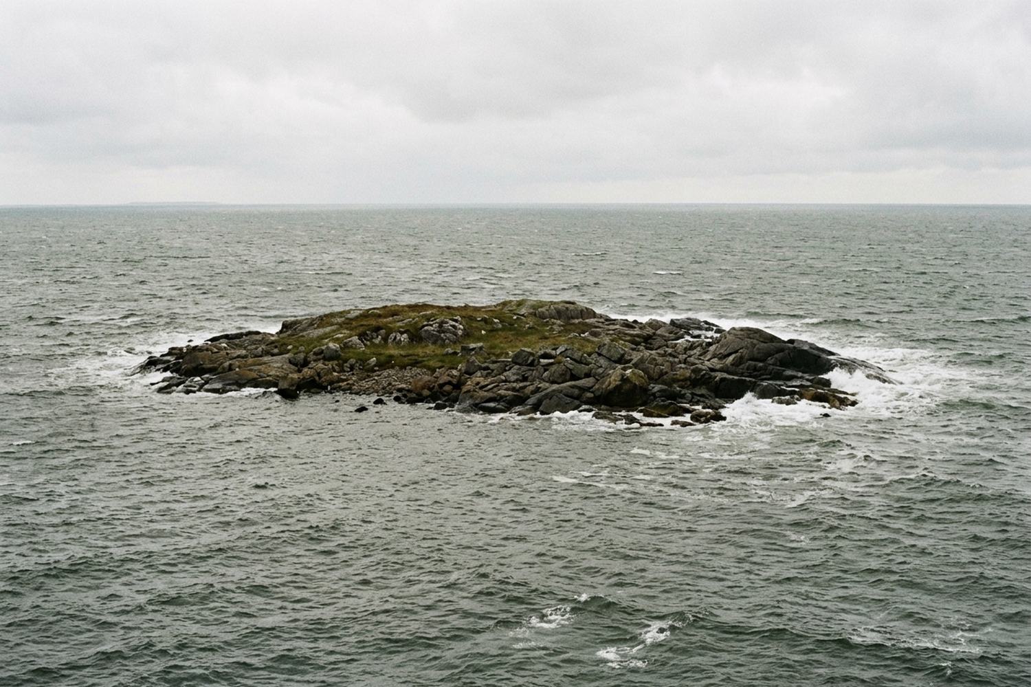 Bare limestone pavement with stone walls and open sea beyond.