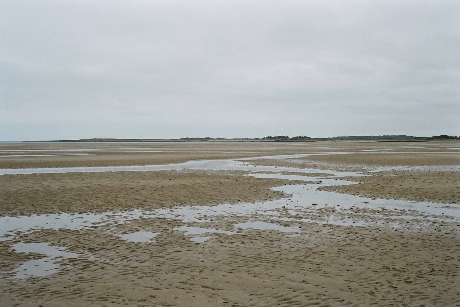 Wide open tidal sand with shallow water standing on it.